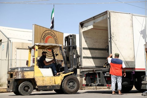 Relief workers unload boxes of medical aid provided by Qatar at Damascus International Airport,