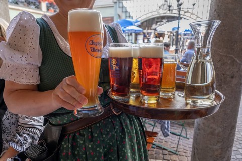 Drinks on a tray are served by a waitress in the beer garden, Munich, Bavaria, Germany