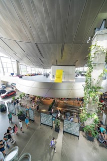 View from above of a modern room with plants and people under a yellow accent, BMW Welt, Munich,