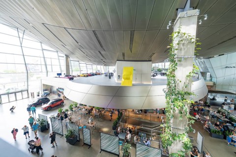 Aerial view of a modern interior with a wall of plants and a crowd of people, BMW Welt, Munich,