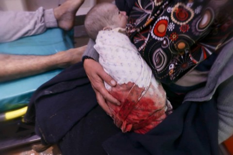 A frightened mother carries her infant after he was pulled from the rubble of a deadly earthquake
