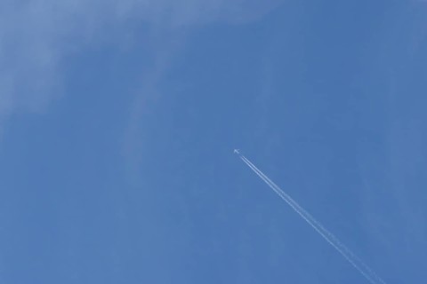 Boeing 737 jet passenger aircraft of Norweign Air with a vapour trial or contrail behind flying in