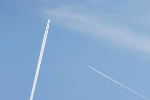 Two jet passenger aircraft with vapour trails or contrails flying in a blue sky, England, United