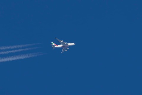 Airbus A380 jet passenger aircraft of Emirates airlines with a vapour trail or contrail flying in a