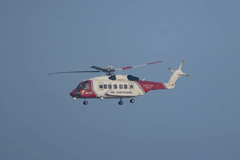 Sikorsky S-92A helicopter of the UK HM Coastguard flying in a blue sky, England, United Kingdom