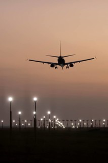 Boeing 737 jet passenger aircraft of Ryanair airlines landing over runway lights at sunset, London
