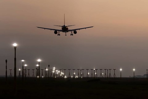 Jet passenger aircraft landing over runway lights at sunset, London Stansted airport, Essex,
