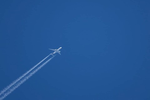 Jet passenger aircraft with a vapour trail or contrail flying in a blue sky, England, United