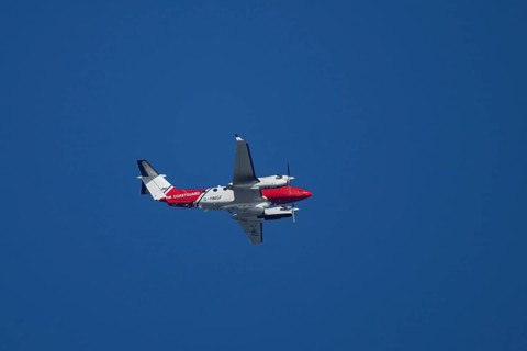 Beech King Air 350 light aircraft of the UK HM Coastguard flying in a blue sky, England, United