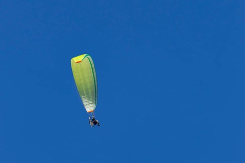 Paraglider flying in a blue sky, England, United Kingdom