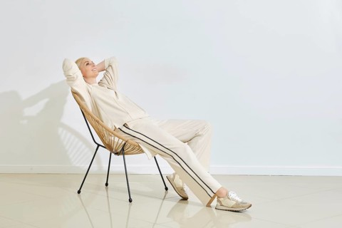 Relaxing in a modern chair, a woman enjoys a quiet moment in a minimalist indoor space