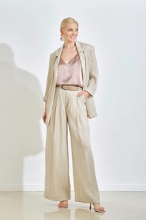 A confident woman stands in a well-lit indoor area, wearing casual outfit featuring a light-hued