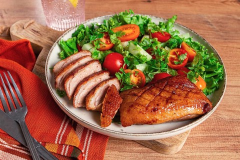 Delicious grilled duck breast served with fresh garden salad and cherry tomatoes at a rustic dining