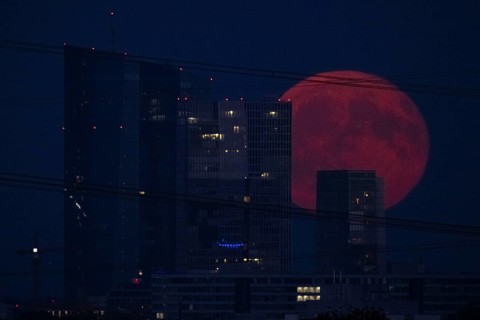 The full moon passes over the Frankfurt banking skyline, Frankfurt am Main, Hesse, Germany