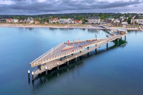 Aerial view over Seebrücke, pier and sandy beach at seaside resort Haffkrug along the Baltic Sea,