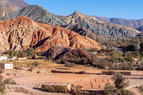 Young people playing football, with coloured hills in the background, erosion, Purmamarca, Jujuy,