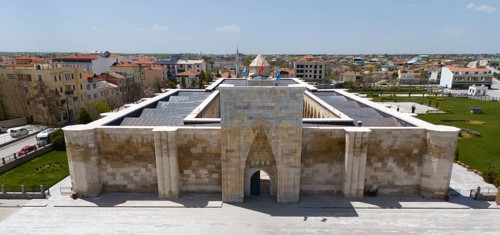Frontal view of a medieval caravanserai with imposing archway in urban surroundings, aerial view,