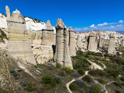 Impressive rock formations under a blue sky in Cappadocia with hiking trails, aerial view, Love