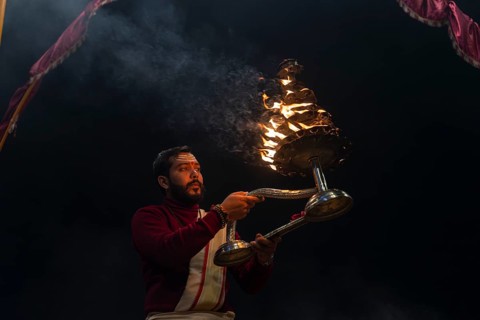 Hindu priest performing the Aarti ritual, holding a burning oil lamp, at the Ganges, Bangali Tola,