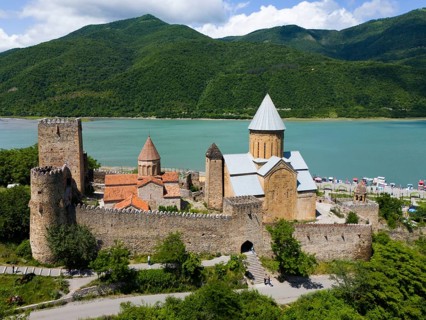 Medieval castle landscape by a body of water with green hills and peaceful atmosphere, aerial view,
