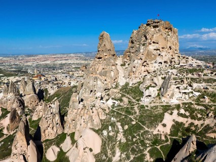 Rocky landscape with ancient rock structures under a clear blue sky in Cappadocia, aerial view,