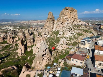 Combination of rock formations and modern buildings under a blue sky in a Turkish town, aerial