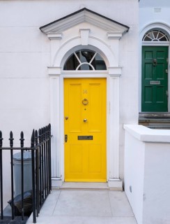 Bright yellow front door with neoclassical triangular pediment, Palladian-style entrance, white