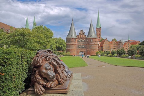 Sleeping lion figure at the historic Holstentor and St. Peter's church tower in Lübeck, Brick