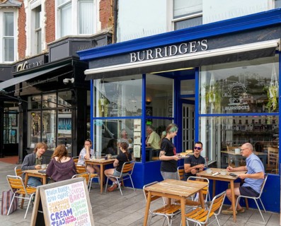People sitting at tables on pavement outside Burridges cafe, Victoria Parade, Torquay, Devon,