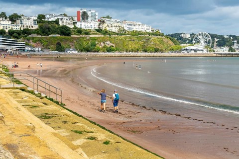 People walking on Torre Abbey Sands sandy beach, Torquay, Devon, England, UK