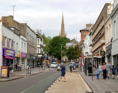 Shops in street of historic buildings, Union Street, Torquay, Devon, England, UK view to church