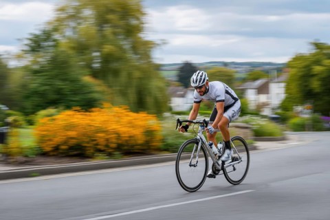 A cyclist, racing cyclist rides his racing bike fast on a road through a rural area, AI generated,
