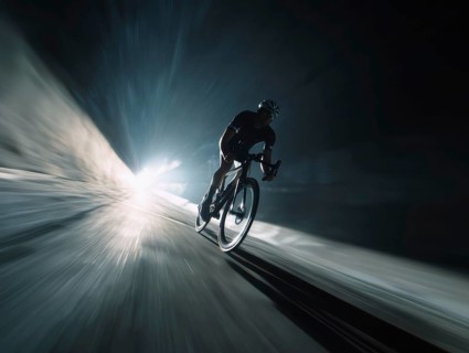 A cyclist, racing cyclist riding his racing bike fast on a sloping road in the dark, motion blur,