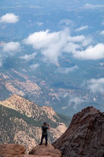 Colorado Springs, Colorado - A man takes photos from the rocks just below the summit of Pikes Peak,
