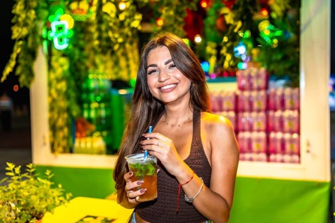 Customer savoring a mojito cocktail at a bustling night market, surrounded by colorful lights and