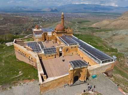 View of a large, well-preserved fortress with a dome in the background of an open landscape, aerial