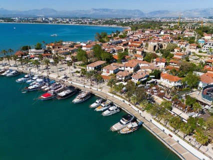 Scenic harbour with boats and palm trees along the coastline of a town, aerial view, harbour, Side,