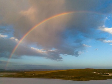A rainbow stretches across a wide landscape under a colourful sky, aerial view, salt lake, Tuz