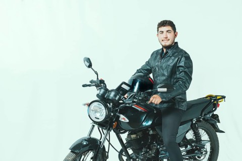 Smiling motorcyclist sitting on his motorcycle holding helmet, isolated. Portrait of handsome biker