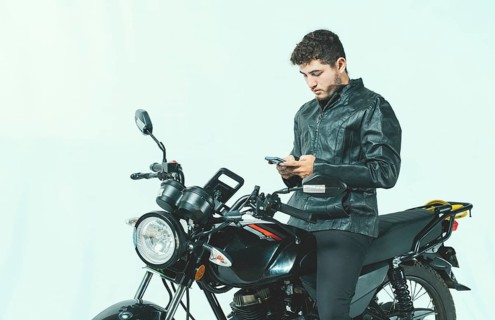 Young motorcyclist using his cell phone while sitting on his motorcycle, isolated. Male biker on a