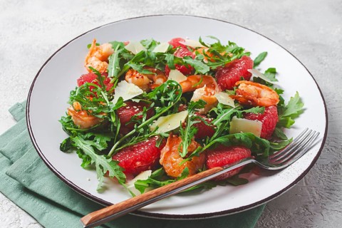 Fresh shrimp salad with arugula, grapefruit, and parmesan served in a bowl