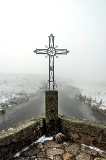 In winter, the Croix du Pont de Marchastel stands proudly amidst a foggy landscape on the Aubrac