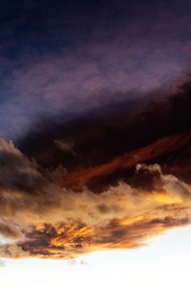 A stunning display of clouds during sunset showcases vibrant orange and deep purple colors fading