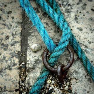 A close-up view reveals a vibrant blue rope intricately intertwined with a metal ring, resting on a