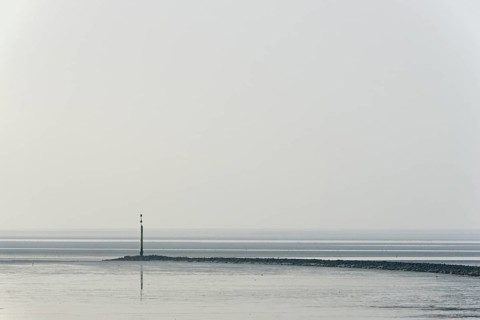 North Sea coast, cloudy winter day, Wadden Sea at low tide, stone groyne with sea mark, North Sea,