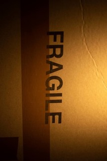 A cardboard package with a clear warning label indicating fragile contents is softly illuminated,