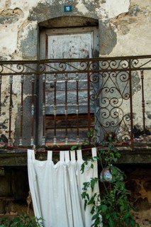 Located in an antique stone structure, this rustic balcony features an ornate railing, flowing