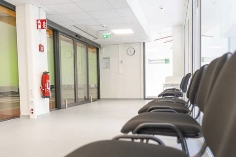 Modern corridor with chairs and escape signs in bright surroundings, Care Connect, vaccination