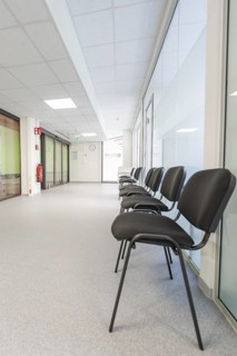 Bright corridor with chairs in the waiting area and modern glass walls, Care Connect, vaccination