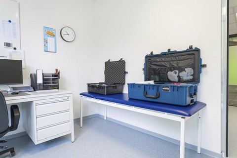 A meeting room with two suitcases, table and clock, Care Connect, vaccination kiosk for refugees,